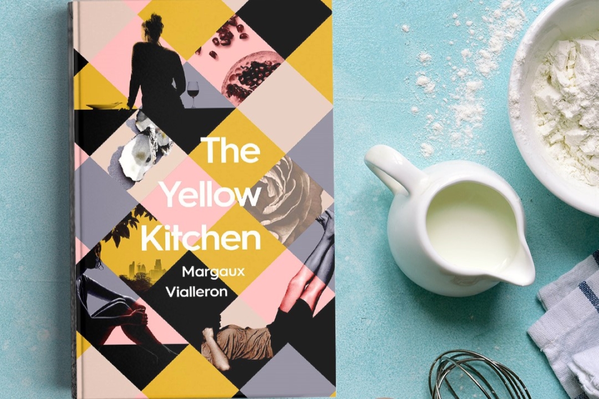"The Yellow Kitchen" cookbook by Margaux Vialleron sits on a turquoise surface next to a white pitcher of milk and bowl of flour.